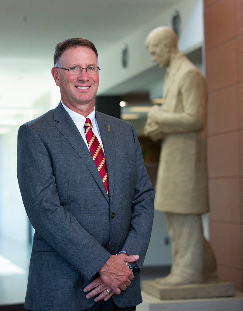 Dr. Dean Grooms standing in front of Gentle Doctor statue