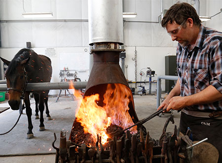 Farrier working on a forge with flames